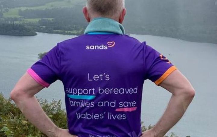 A man wearing a Sands t-shirt looking out over the Lake District