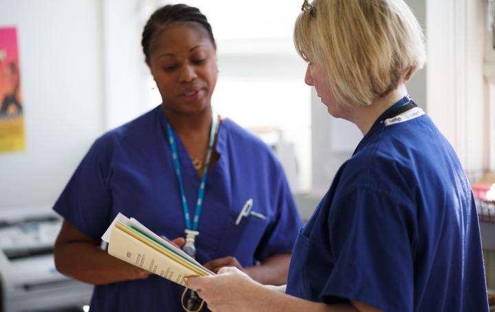 Two midwives in a hospital glancing at information