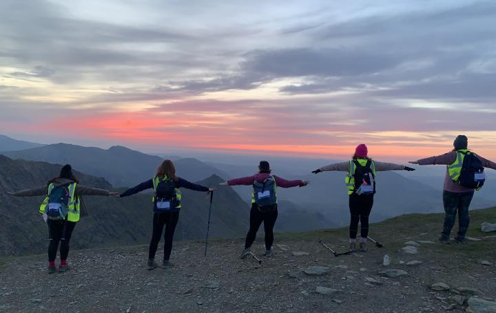 Group of people, arms out, sunset in the background