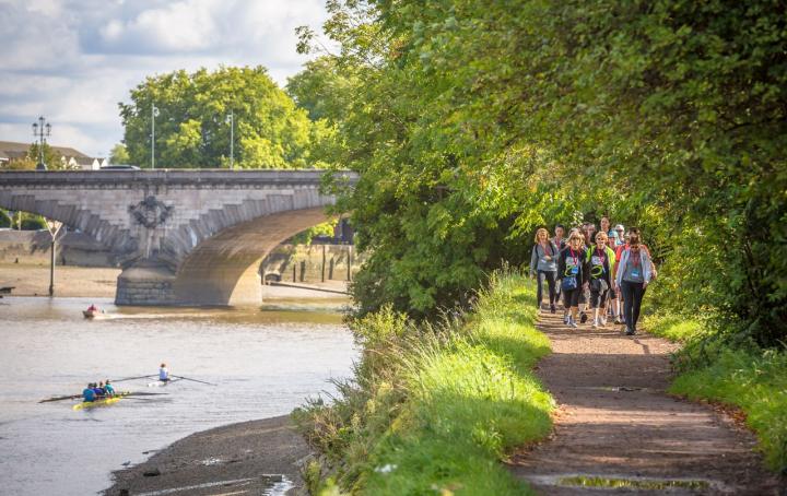 A river and bridge with people walking on a path.