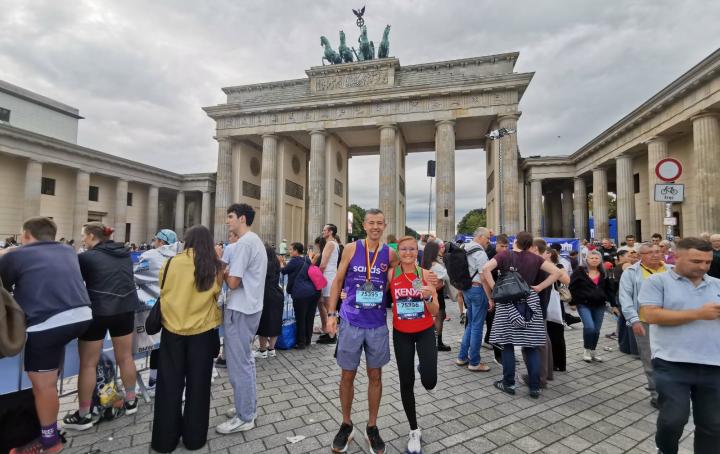 Man and woman standing in front of the brandenburg gate with a crowd of people