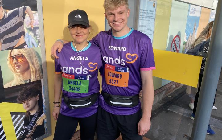 Two runners standing close to each other smiling, and wearing purple t-shirts