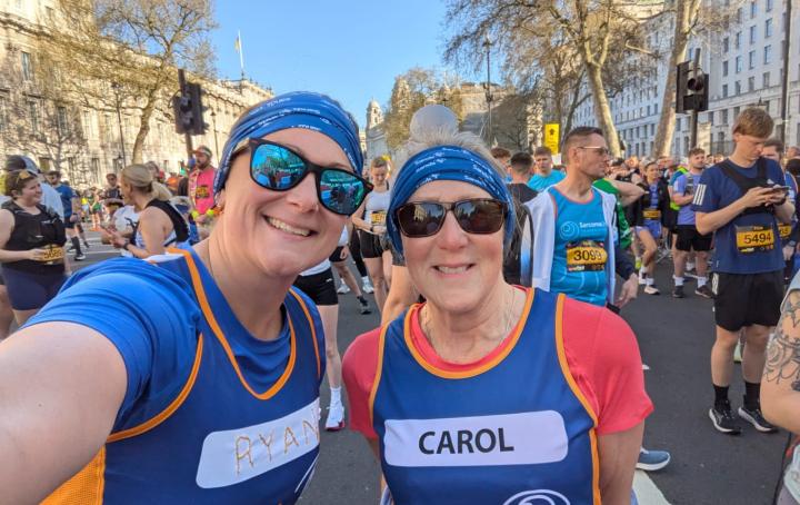 Two female Sands runners, posing for a photo wearing Sands branded running tops and bandanas.