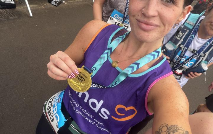 woman holding medal at a running event