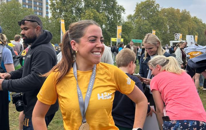 Female runner wearing royal park finisher t-shirt in yellow and wearing their race medal