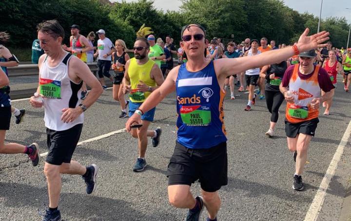 A male Sands runner, running and waving.