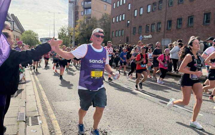 A road with people running, a man running and high fiving crowd