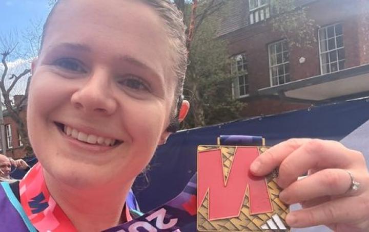 A female runner holding up a medal