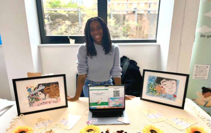 An image of Helena stood behind a desk displaying her personalised baby loss books