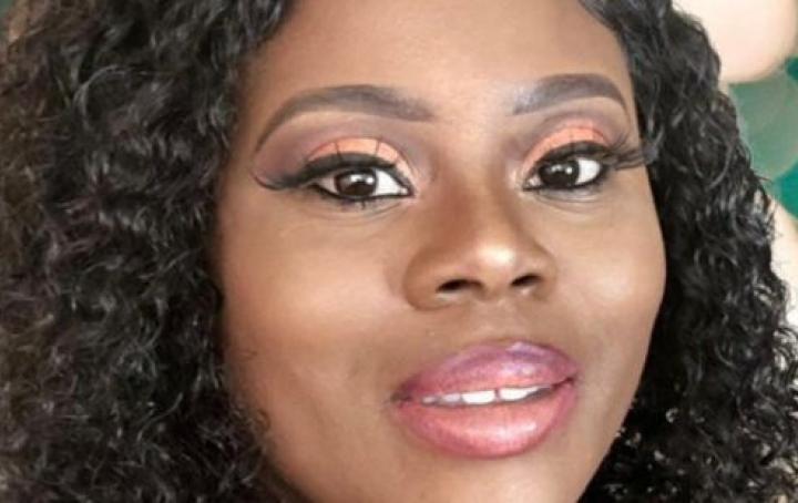 Photograph of Tolu smiling at the camera n a plain background