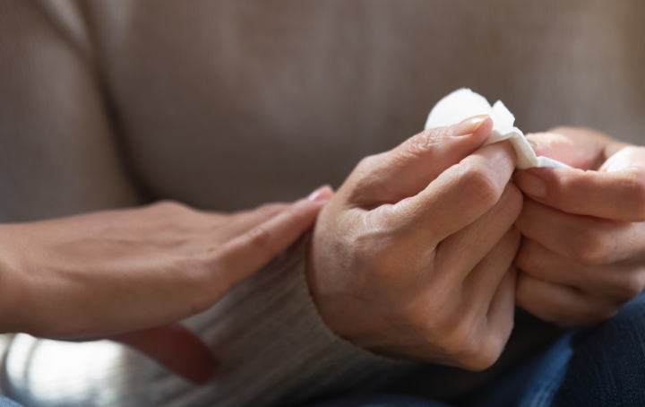 Close up of someone's hands holding a tissue, and someone else reaching out in support.