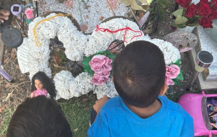Two boys placing a yellow and red rakhi on their sisters resting place
