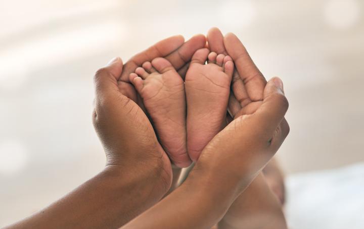 Two adult hands hold a baby's feet