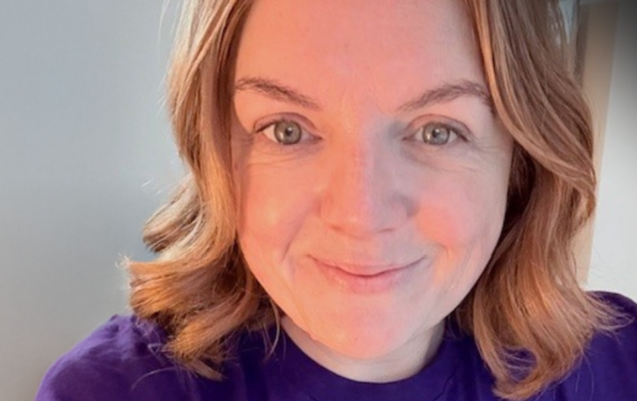 Ruth smiling wearing a purple Sands branded t shirt