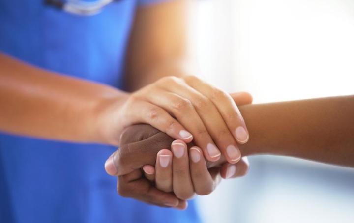 A nurse holds a woman's hand